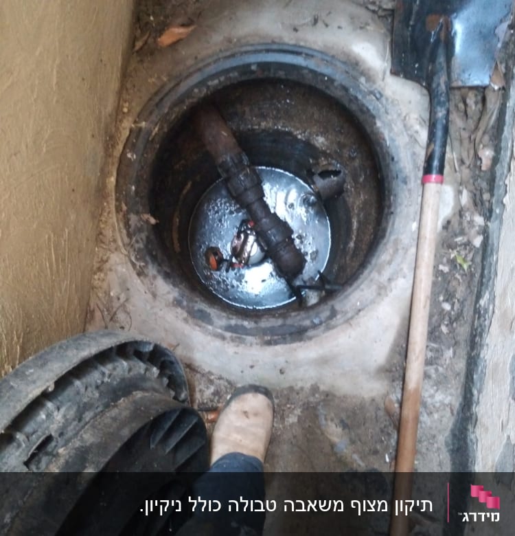 בור ביוב פתוח עם צינור וכלי עבודה